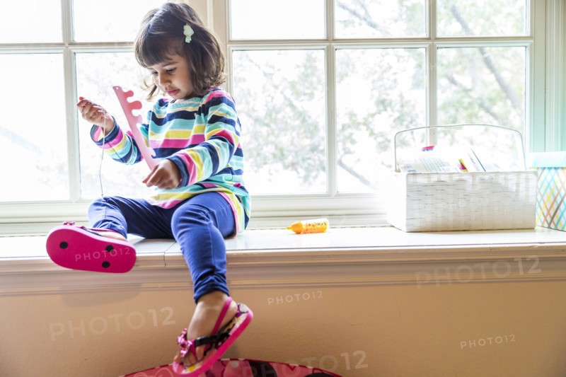 Girl playing with toys in windowsill