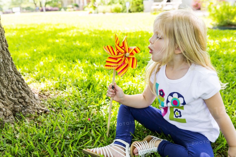 Caucasian girl playing with pinwheel in backyard