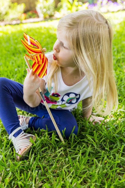 Caucasian girl playing with pinwheel in backyard