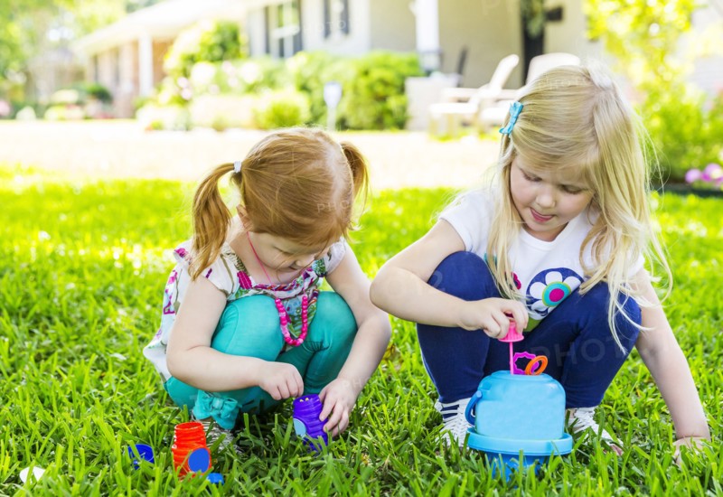Caucasian sisters blowing bubbles in backyard