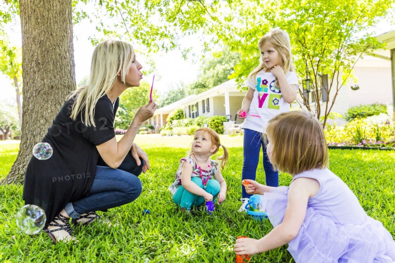 Caucasian mother and daughters blowing bubbles in backyard