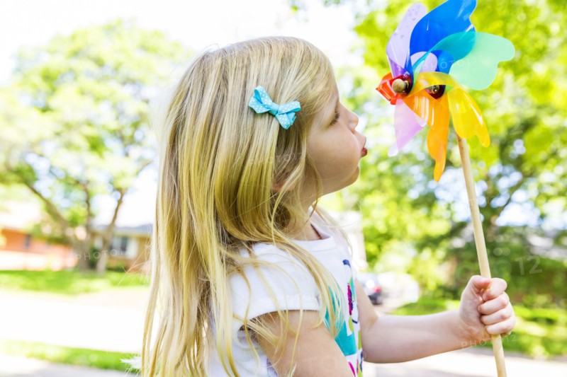 Caucasian girl playing with pinwheel in backyard