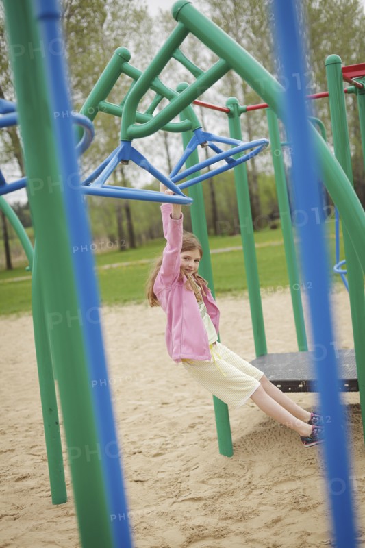 Caucasian girl hanging from structure in playground