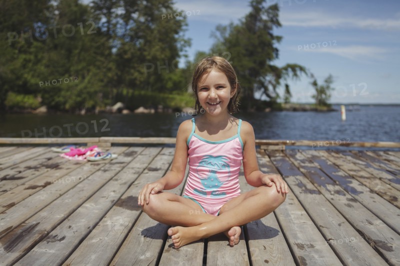 Caucasian girl sitting on wooden dock over lake