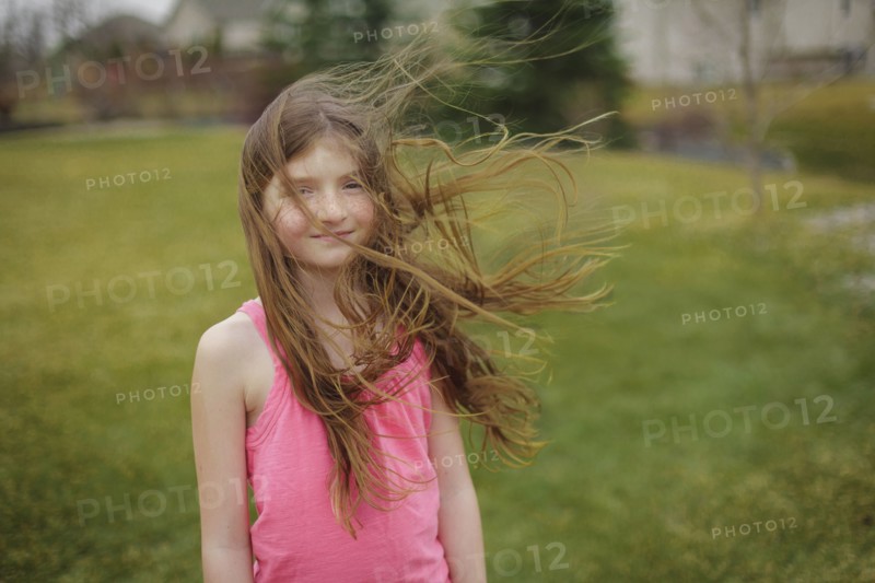 Hair of Caucasian girl blowing in wind in backyard