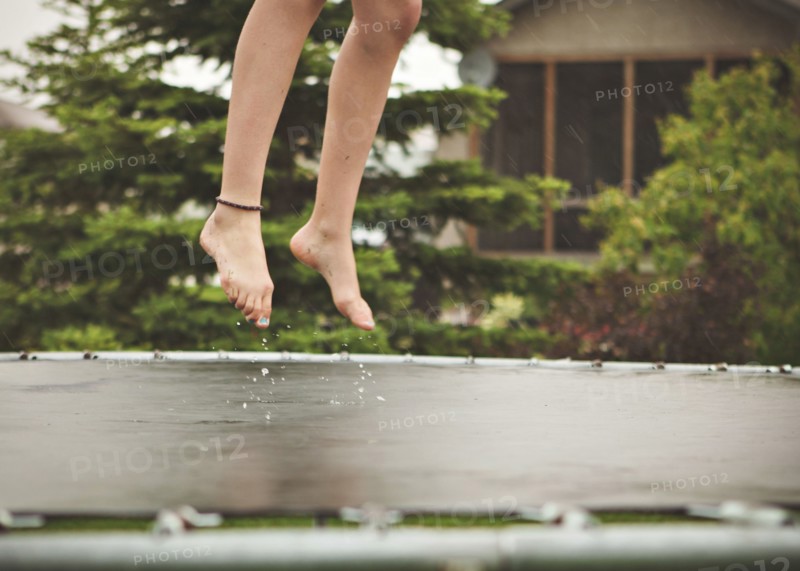 Caucasian girl jumping on wet trampoline