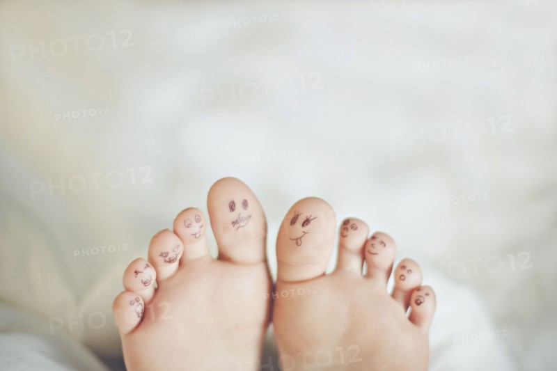 Toes of Caucasian girl with smiley face drawings