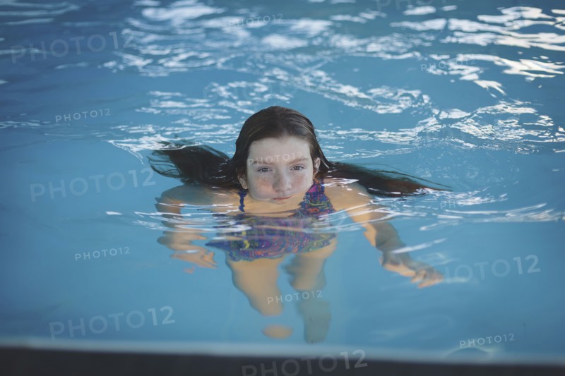 Caucasian girl floating in swimming pool