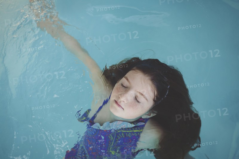 Caucasian girl floating in swimming pool