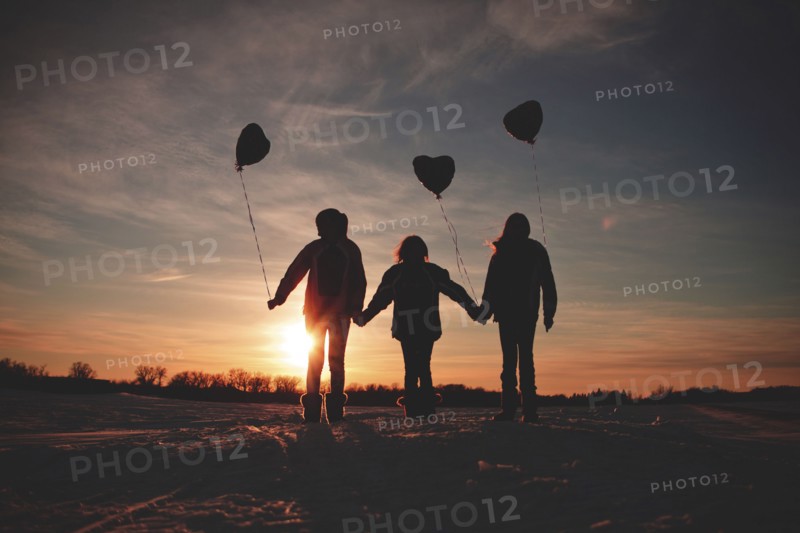 Caucasian girls walking with balloons at sunset
