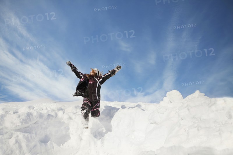 Caucasian girl jumping on snowy hillside