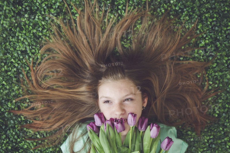 Caucasian girl with tulips laying in grass