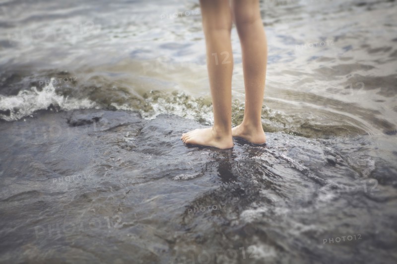Caucasian girl standing in ocean waves