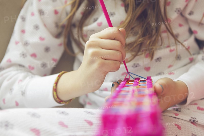 Caucasian girl knitting with rainbow loom