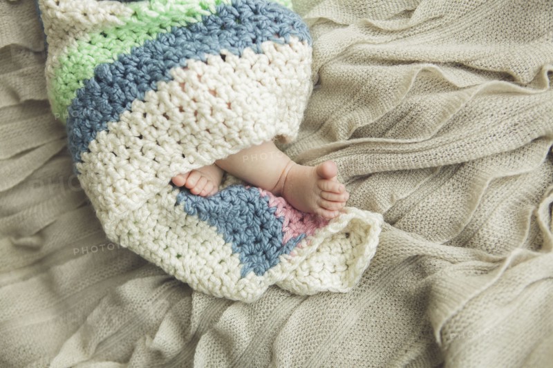 Close up of feet of newborn baby wrapped in blanket