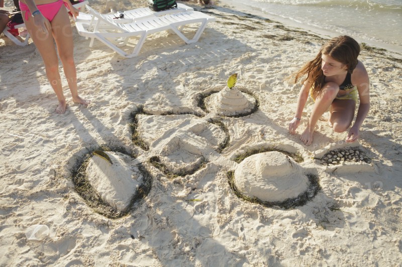 Caucasian teenage girl building sandcastle on beach
