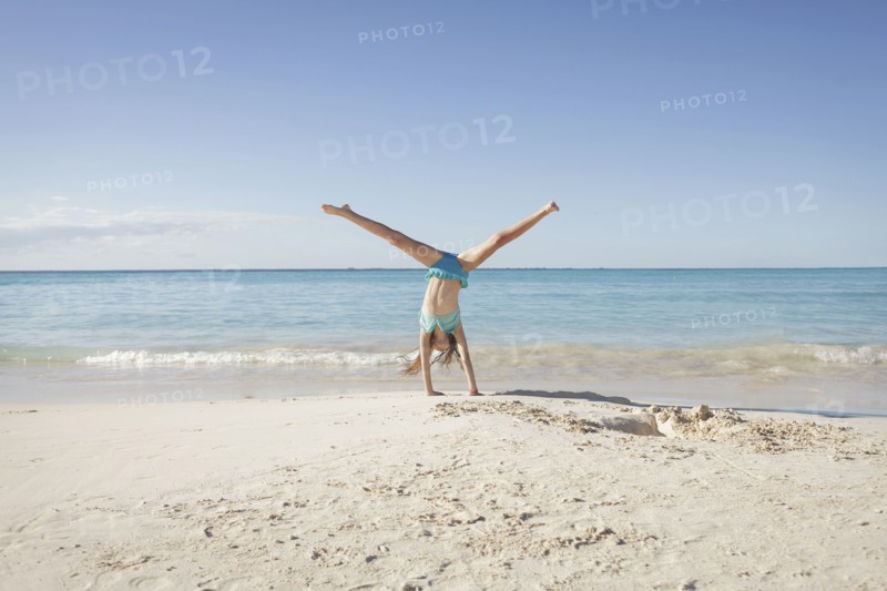 Caucasian girl doing cartwheel on beach