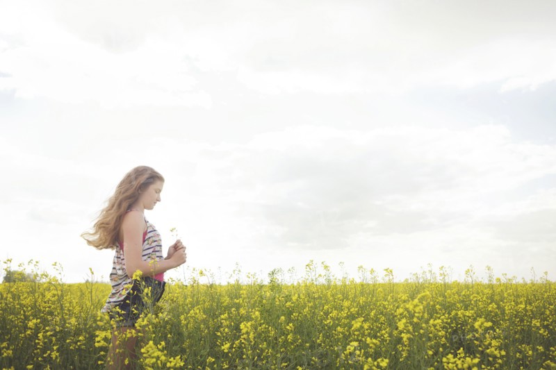Caucasian teenage girl standing in field of flowers