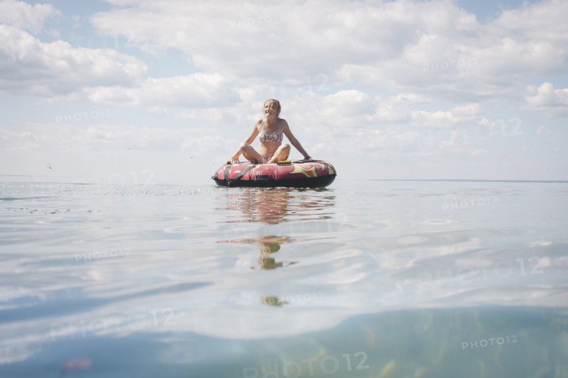Caucasian teenage girl floating in inner tube on lake