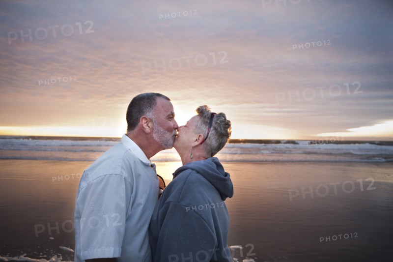 Caucasian couple kissing on beach at sunset