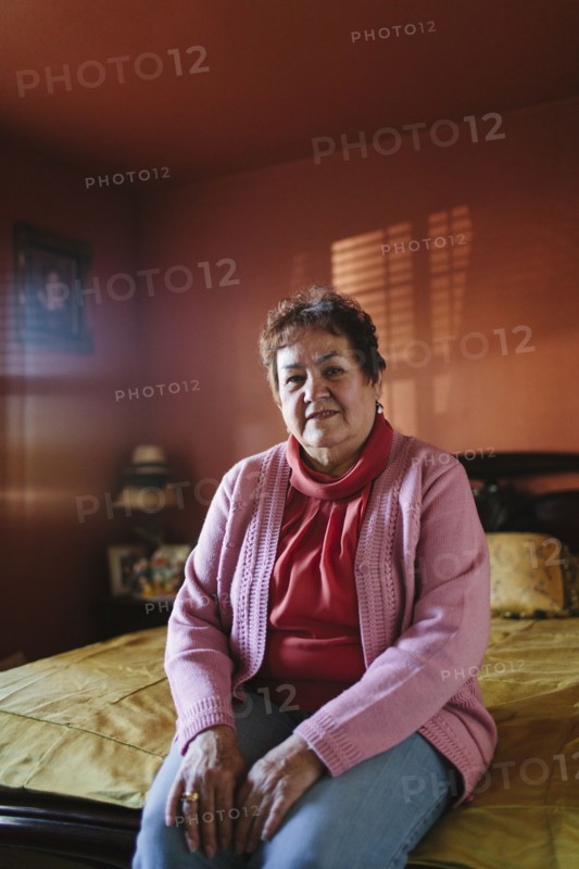 Hispanic woman sitting on bed