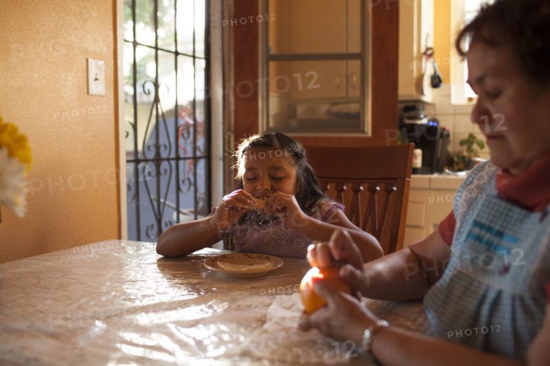 Hispanic grandmother and granddaughter eating in kitchen