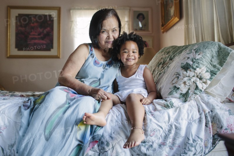 Grandmother and granddaughter hugging on bed