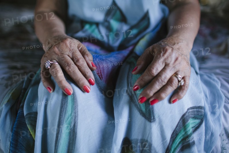 Close up of hands of older woman resting on knees