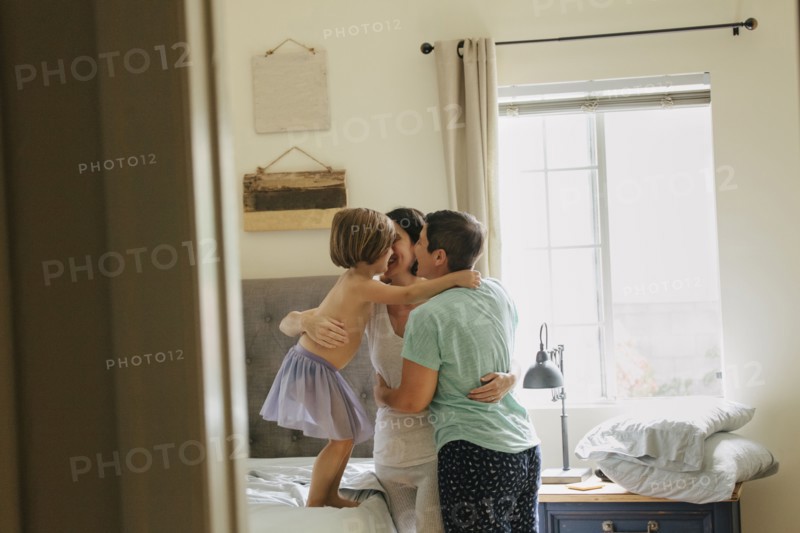 Caucasian family hugging in bedroom