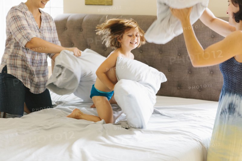 Caucasian family having pillow fight in bedroom
