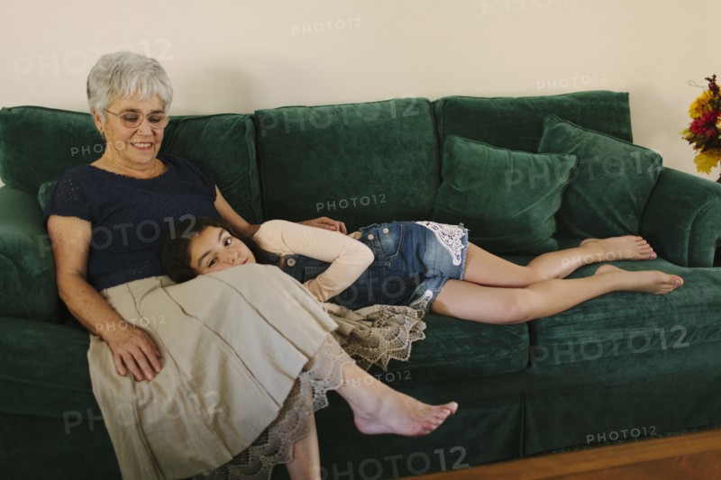 Grandmother and granddaughter sitting on sofa in living room