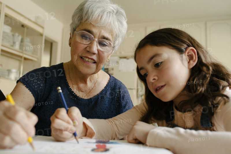 Grandmother and granddaughter drawing at table