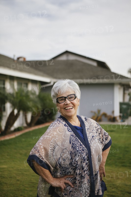 Older woman standing with hands on hips in backyard