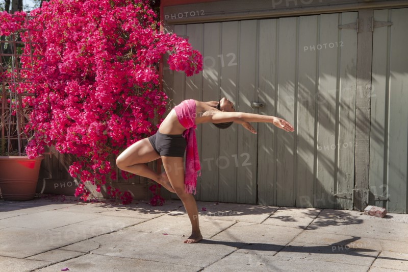 Woman practicing yoga near flowers and fence