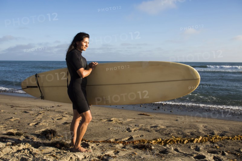 Hispanic surfer carrying surfboard on beach