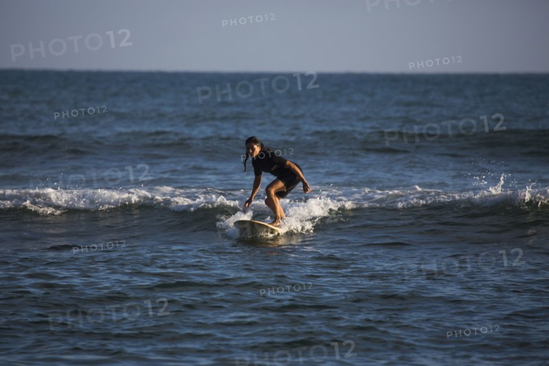 Hispanic woman surfing in ocean