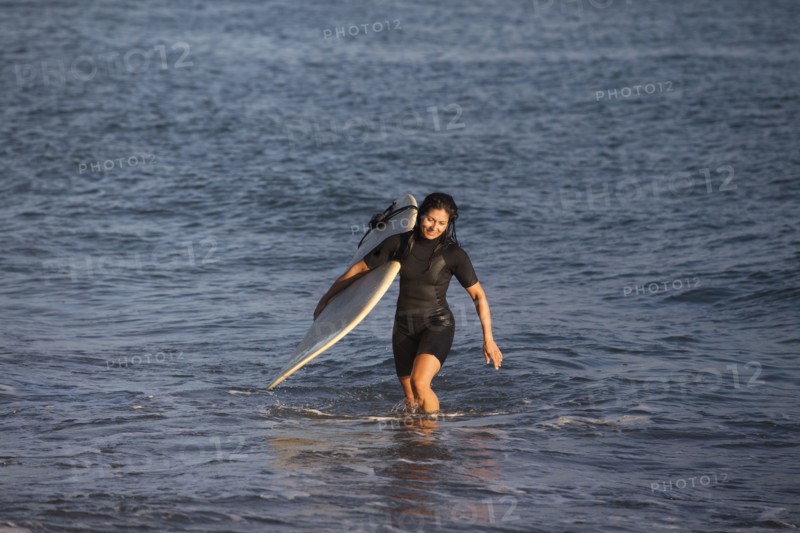Hispanic surfer carrying surfboard in ocean