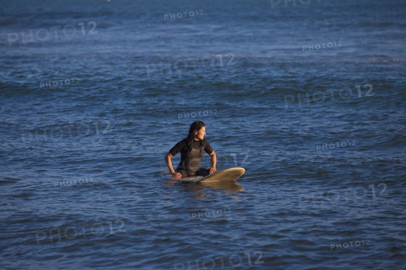 Hispanic surfer floating on surfboard in ocean
