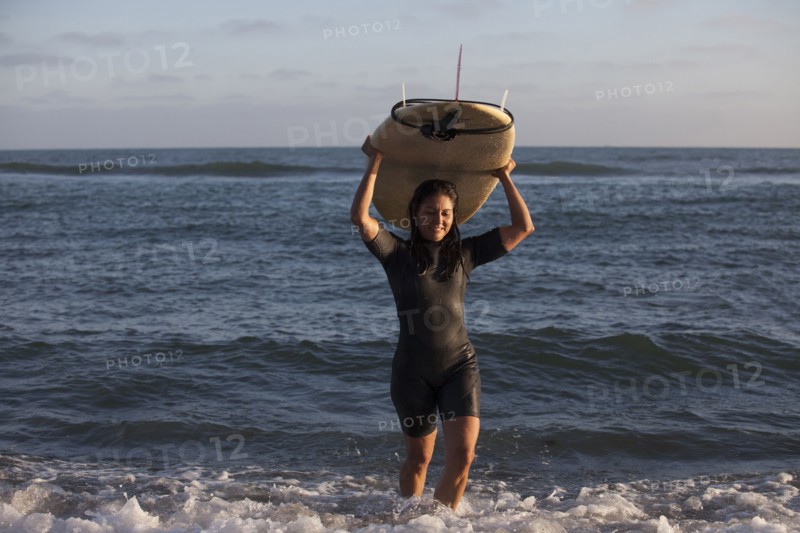 Hispanic surfer carrying surfboard in ocean