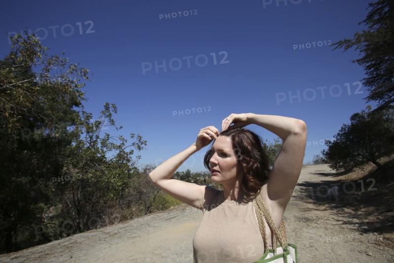Caucasian woman pinning her hair on dirt path