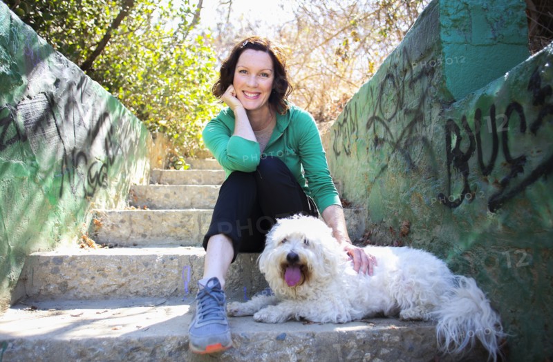 Caucasian woman petting dog on staircase with graffiti
