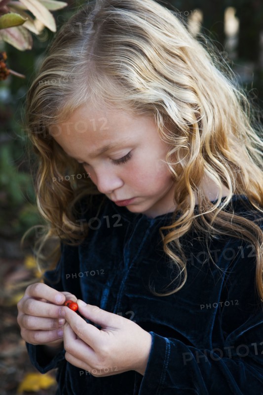 Close up of girl examining berry outdoors