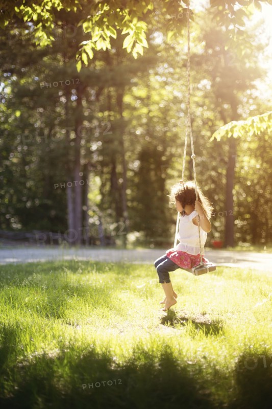 Girl sitting on swing in field