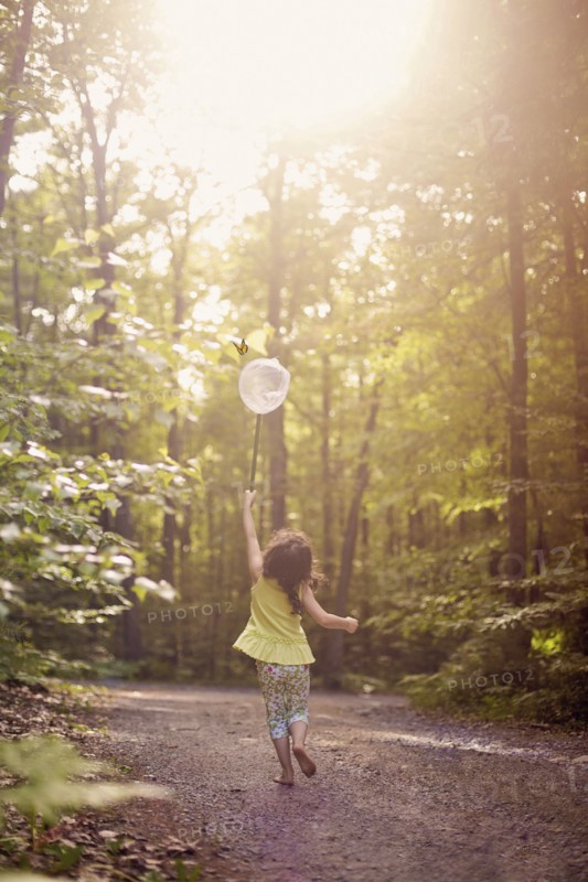 Girl playing with butterfly net in forest