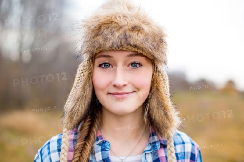 Caucasian teenage girl wearing fur hat in field