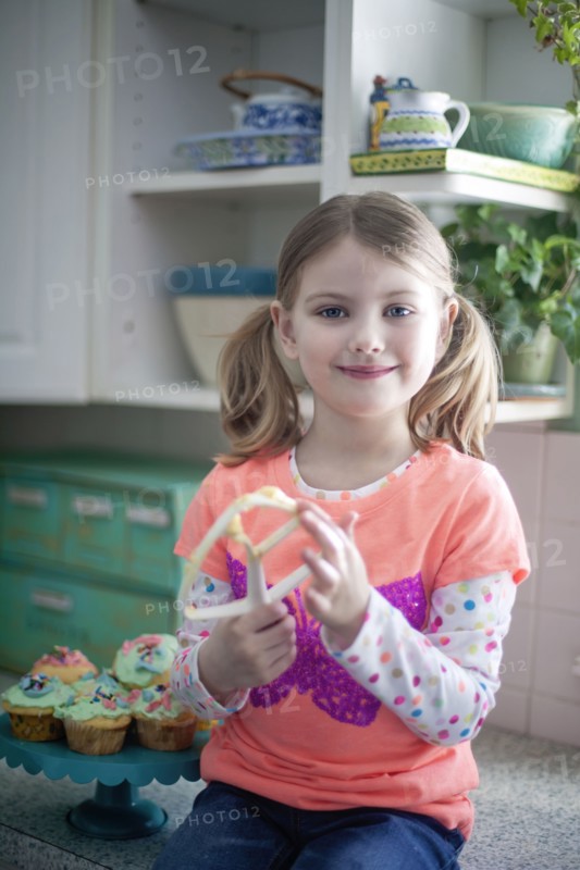 Caucasian girl licking mixing paddle in kitchen