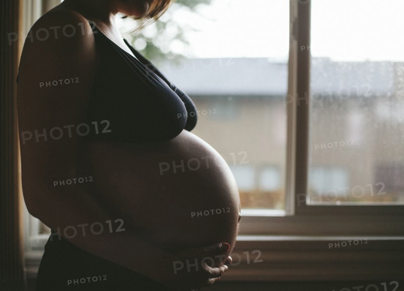 Pregnant Caucasian woman standing at window