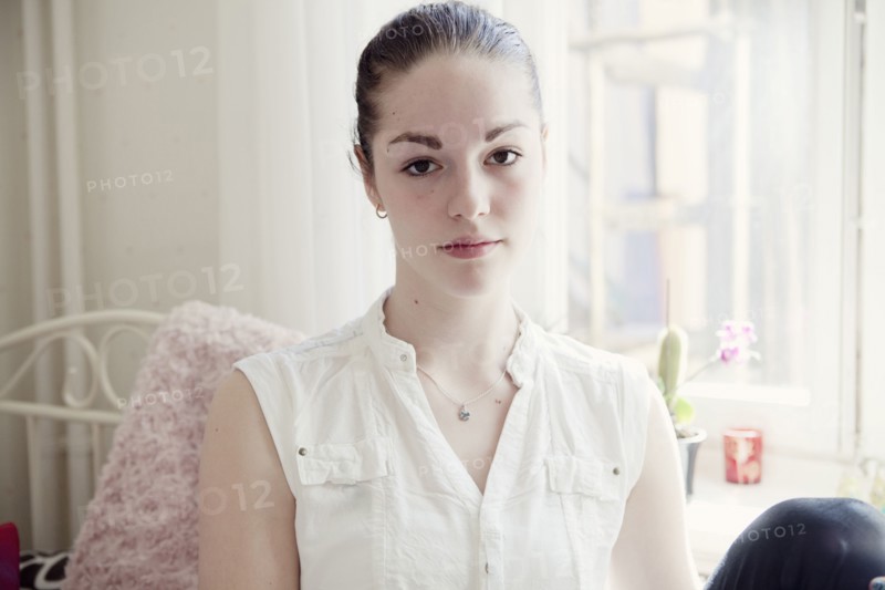 Caucasian teenage girl sitting on bed