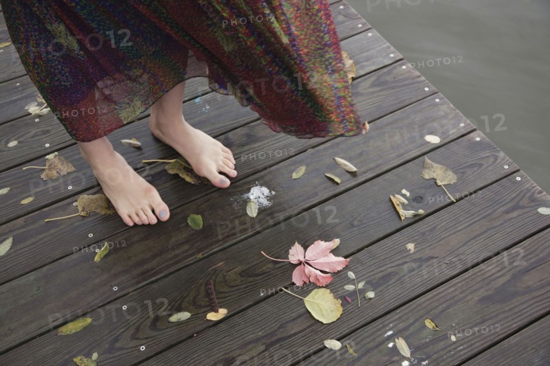 Woman standing barefoot on wooden dock