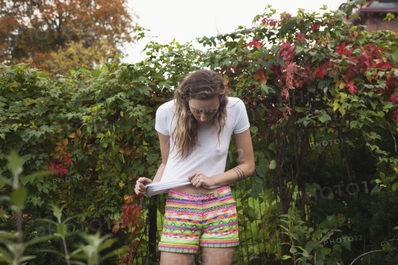 Woman stretching her shirt in shrub bushes